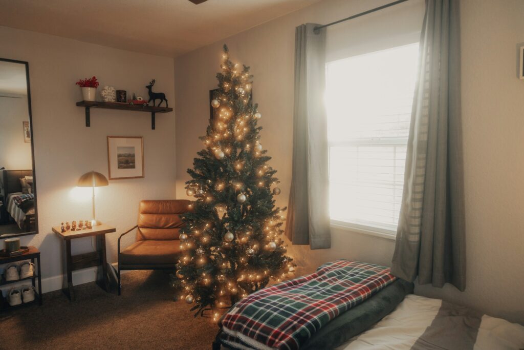 An idea of a cozy NYC apartment decorated for the holidays with a lit Christmas tree, tidy living space, and clean surfaces, illustrating a holiday cleaning checklist for NYC apartments. Image by Elijah Pilchard via www.unsplash.com